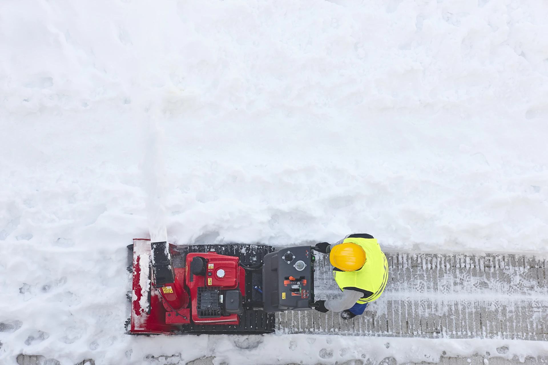 Worker cleaning snow on the sidewalk with a snowblower. Winterti Worker cleaning snow on the sidewalk with a snowblower. Winterti